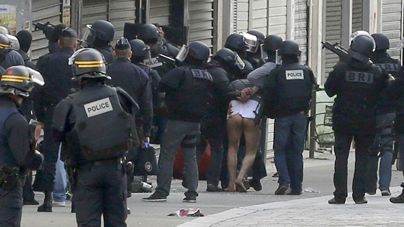 Uno de los detenidos es extraído del edificio desnudo de cintura para abajo
