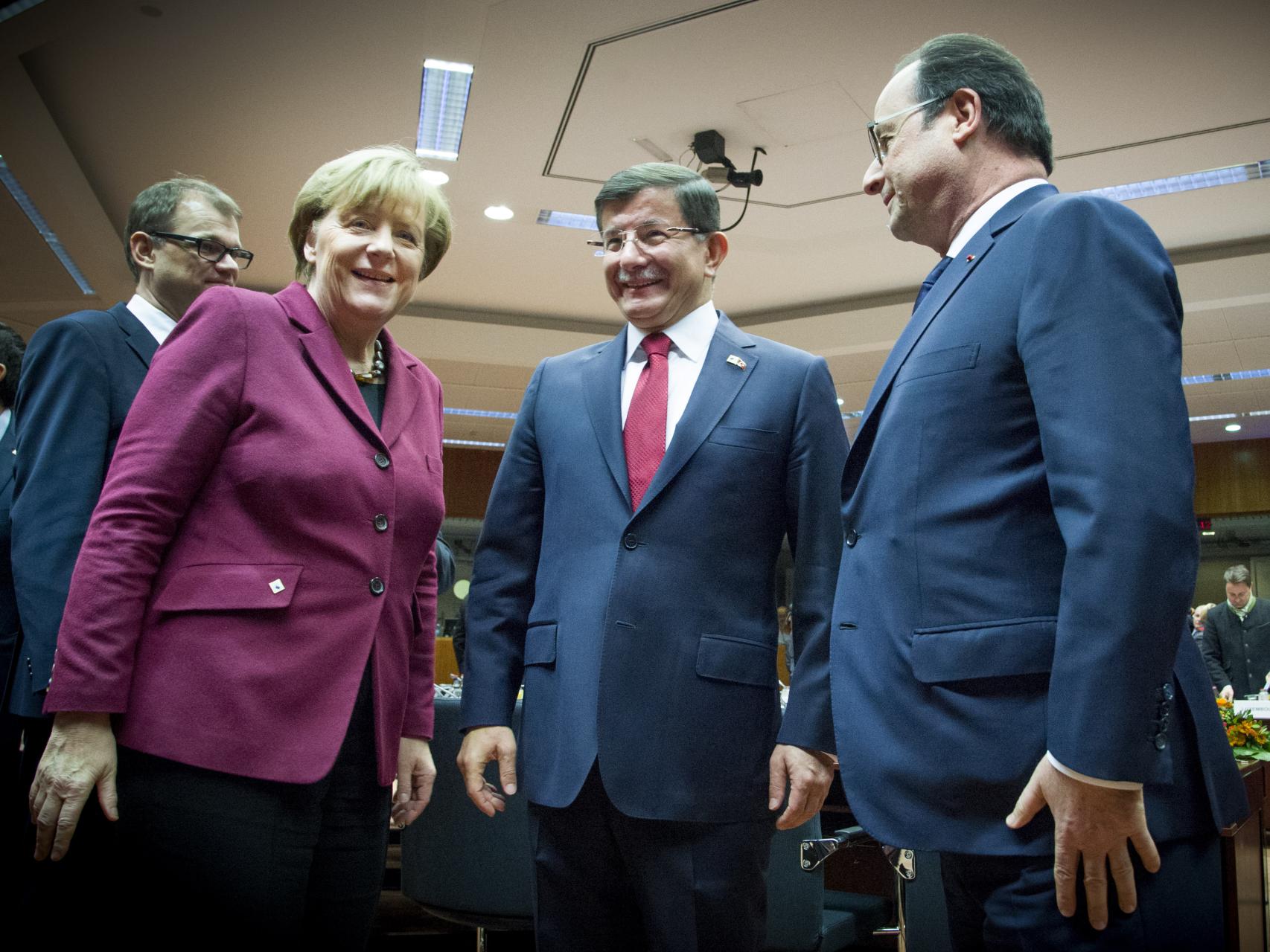 El primer ministro turco, Ahmed Davutoglu, con la canciller Angela Merkel y el presidente galo François Hollande