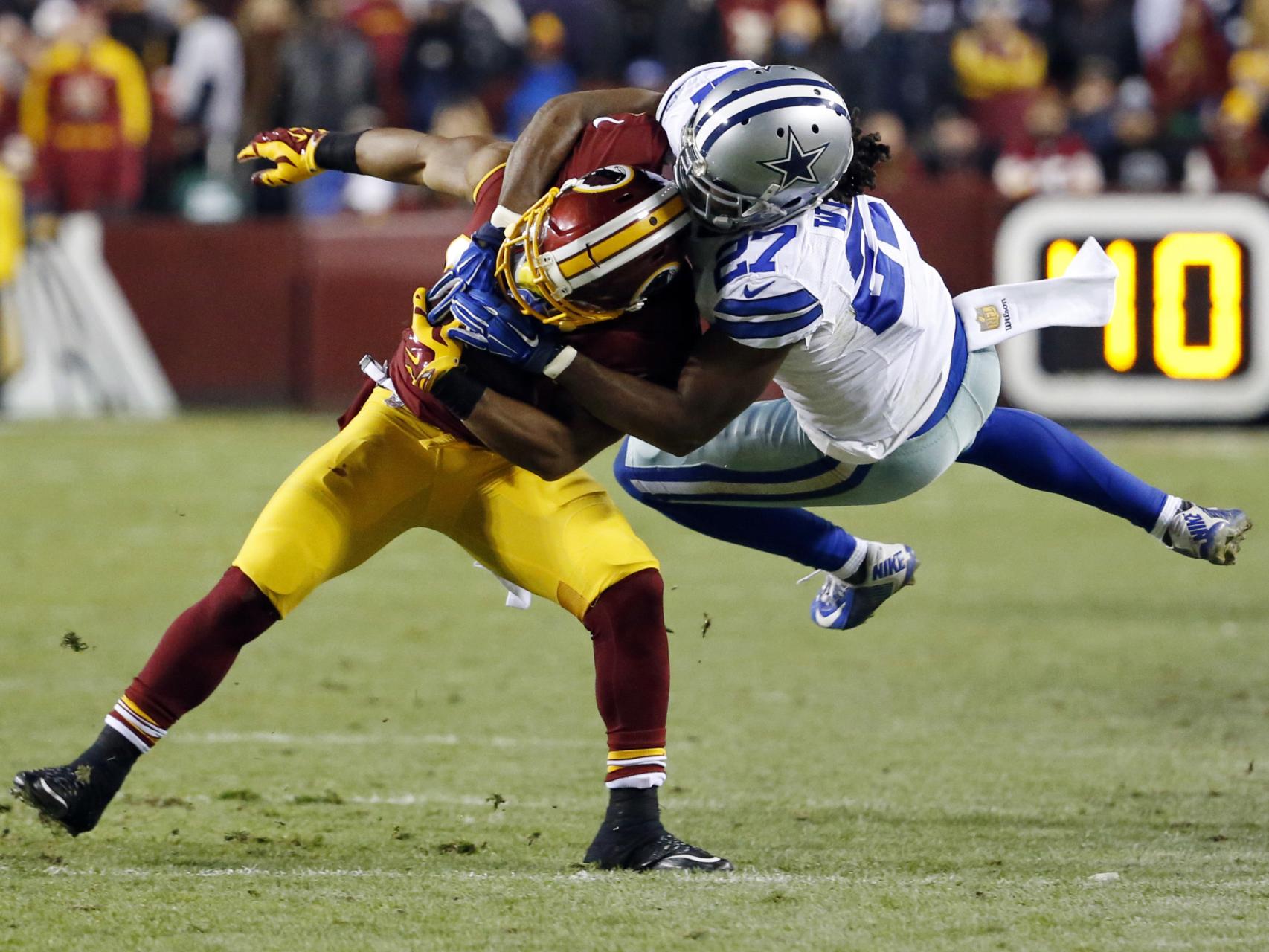 Wilcox de los Cowboys intenta placar a Thompson, de los Redskins.