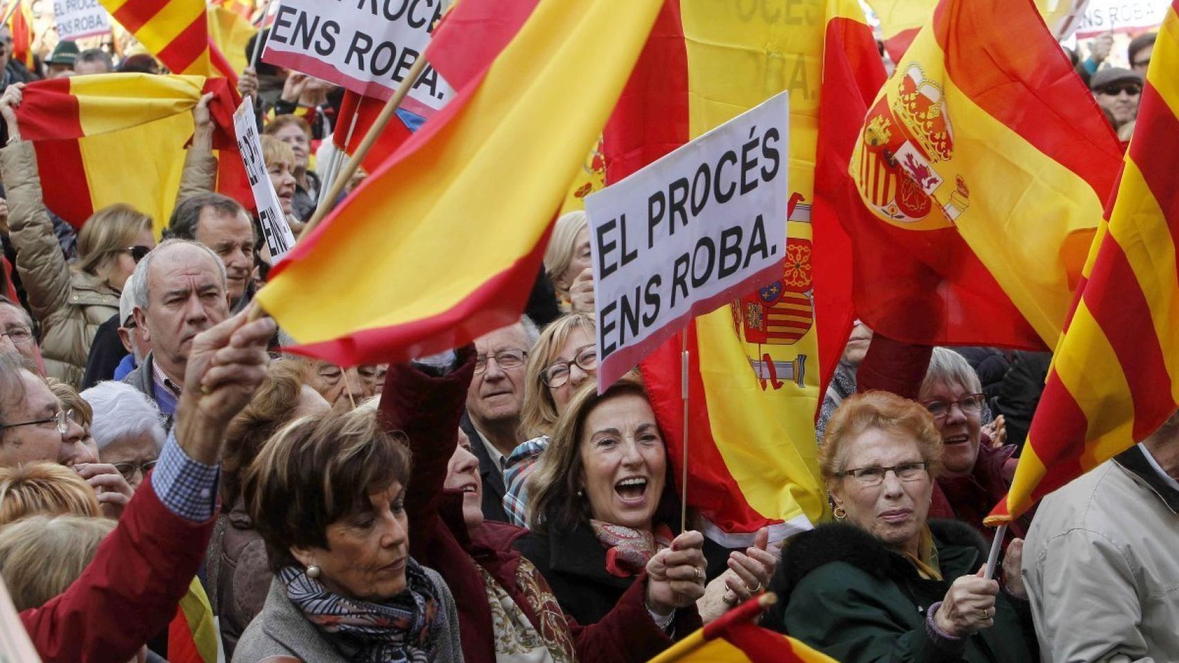 Algunos manifestantes con pancartas en las que se lee 'El procés ens roba'.