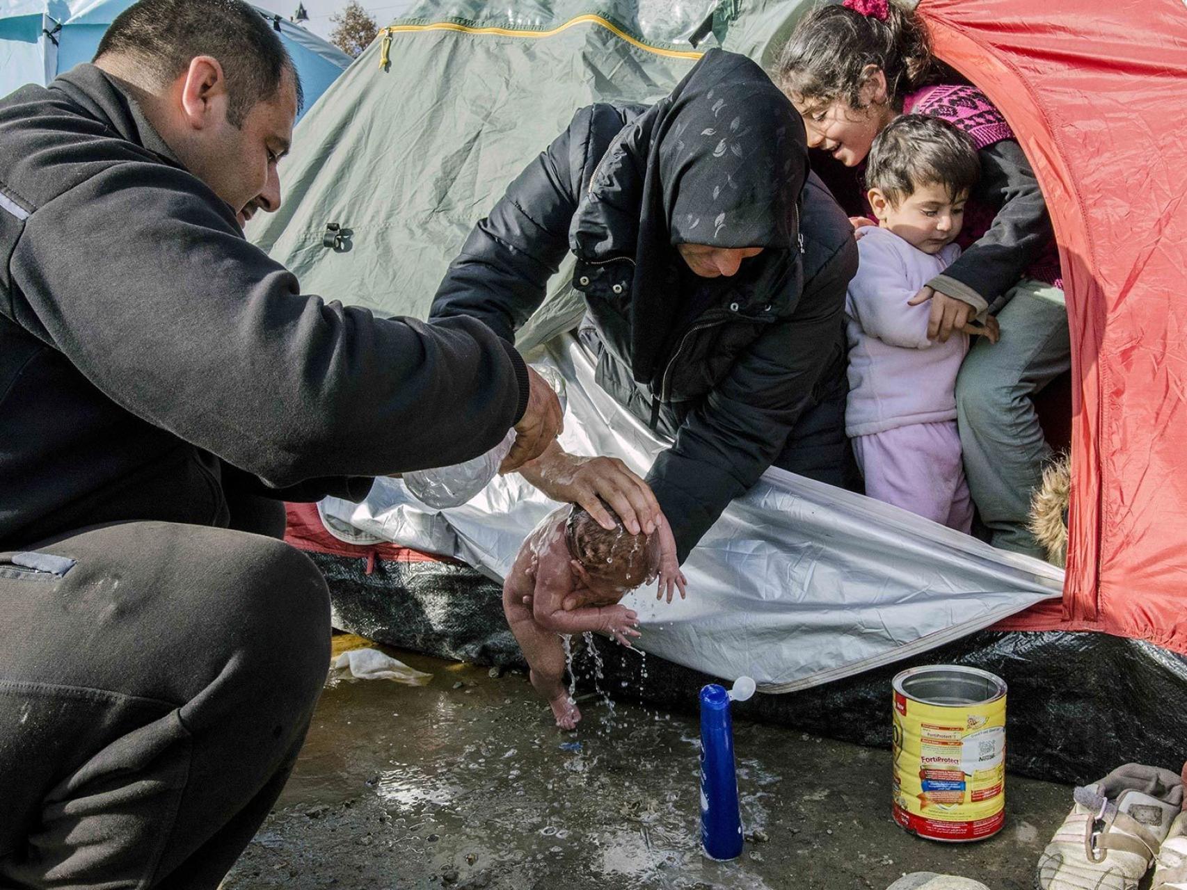 Los padres de Bayan la bañan frente a su tienda de campaña en Idomeni.