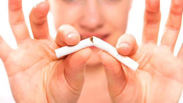 Una mujer rompe un cigarrillo.