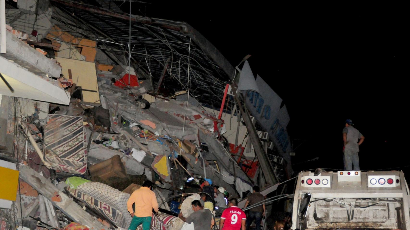 Personas buscan entre escombros en la localidad de Manta tras el sismo.
