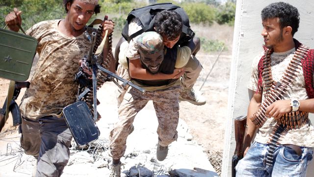 Un miliciano de las fuerzas que apoyan al Gobierno libio ayuda a un herido durante la batalla en Sirte.