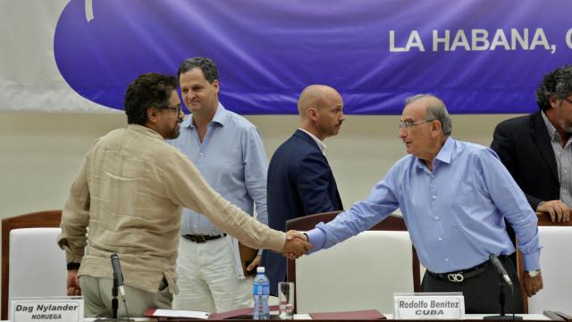 El representante del Gobierno (d) y el de las Farc (i) se dan la mano.