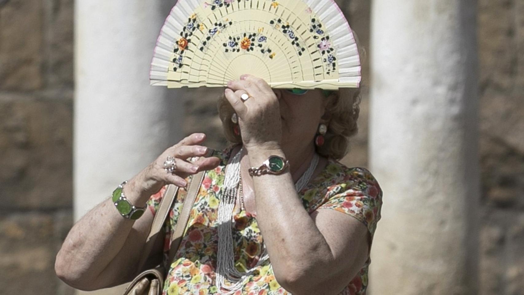 Una mujer se protege del sol con un abanico.