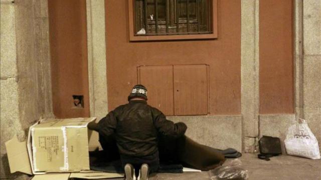 Un indigente se dispone a pasar la noche en un porche.