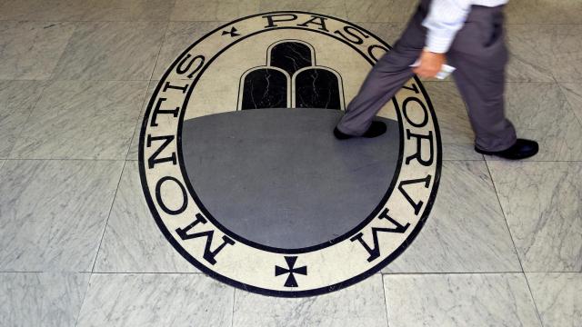 A man walks on a logo of the Monte Dei Paschi Di Siena bank in Rome