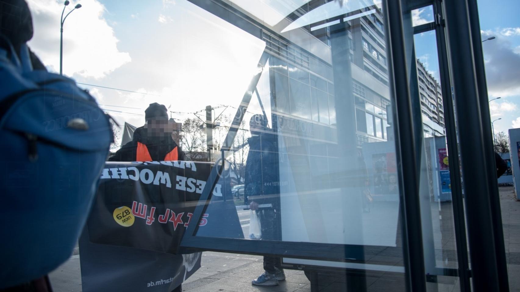 Vermibus retira un cartel de una marquesina.