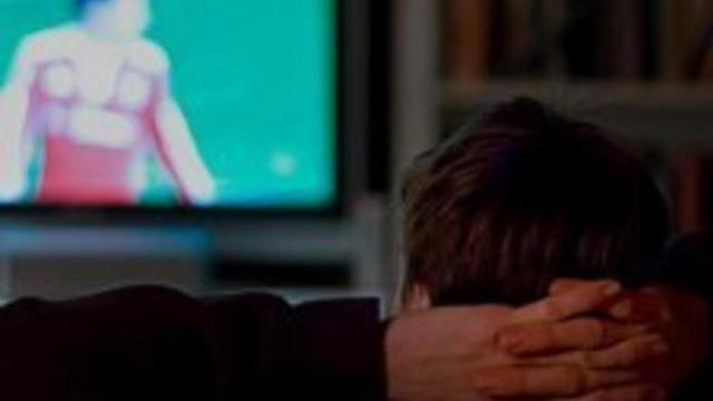 Un hombre viendo un partido de fútbol.