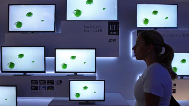 Una chica pasa ante un expositor de televisores.