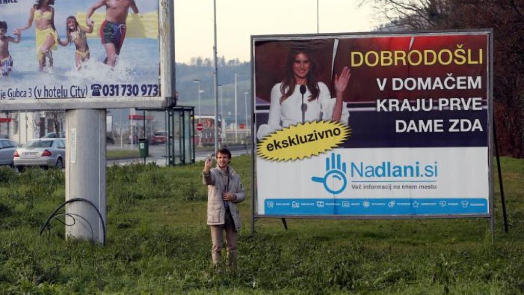 Un turista se hace un selfie ante el cartel con la foto de Trump a la entrada de su pueblo natal