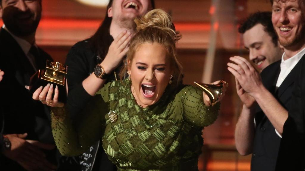 Momento en el que Adele enseña a Beyoncé el galardón partido.