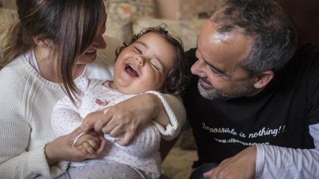 Alba, sonriente entre sus padres, Belén y Sergio.