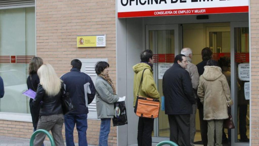 Un grupo de personas hacen cola en la entrada de una oficina de empleo.