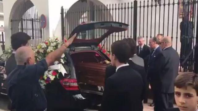 Varias personas alzan el brazo ante el féretro.