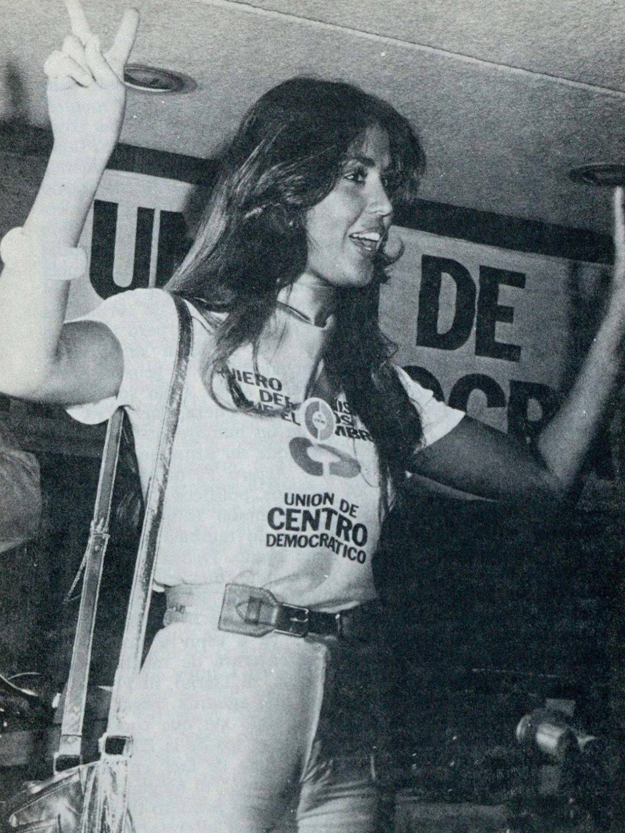 La Chica-Centro levanta las dos manos haciendo el signo de la victoria.