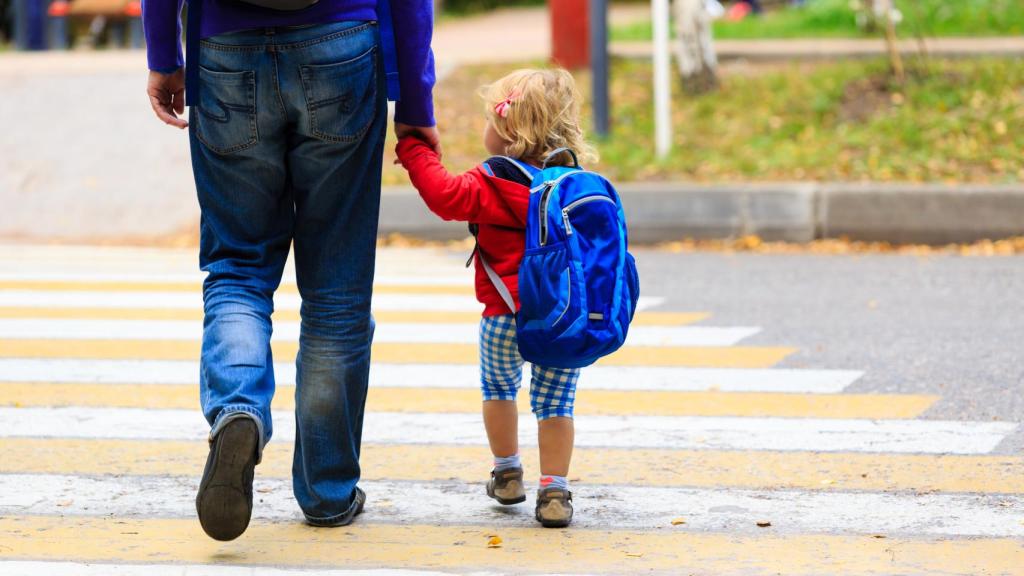 Un niño camina de la mano junto a su padre.