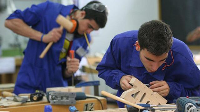 Dos jóvenes trabajando con una pieza madera.