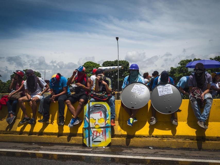 Varios escuderos descansan sentados en una mediana de la autopista Francisco Fajardo.