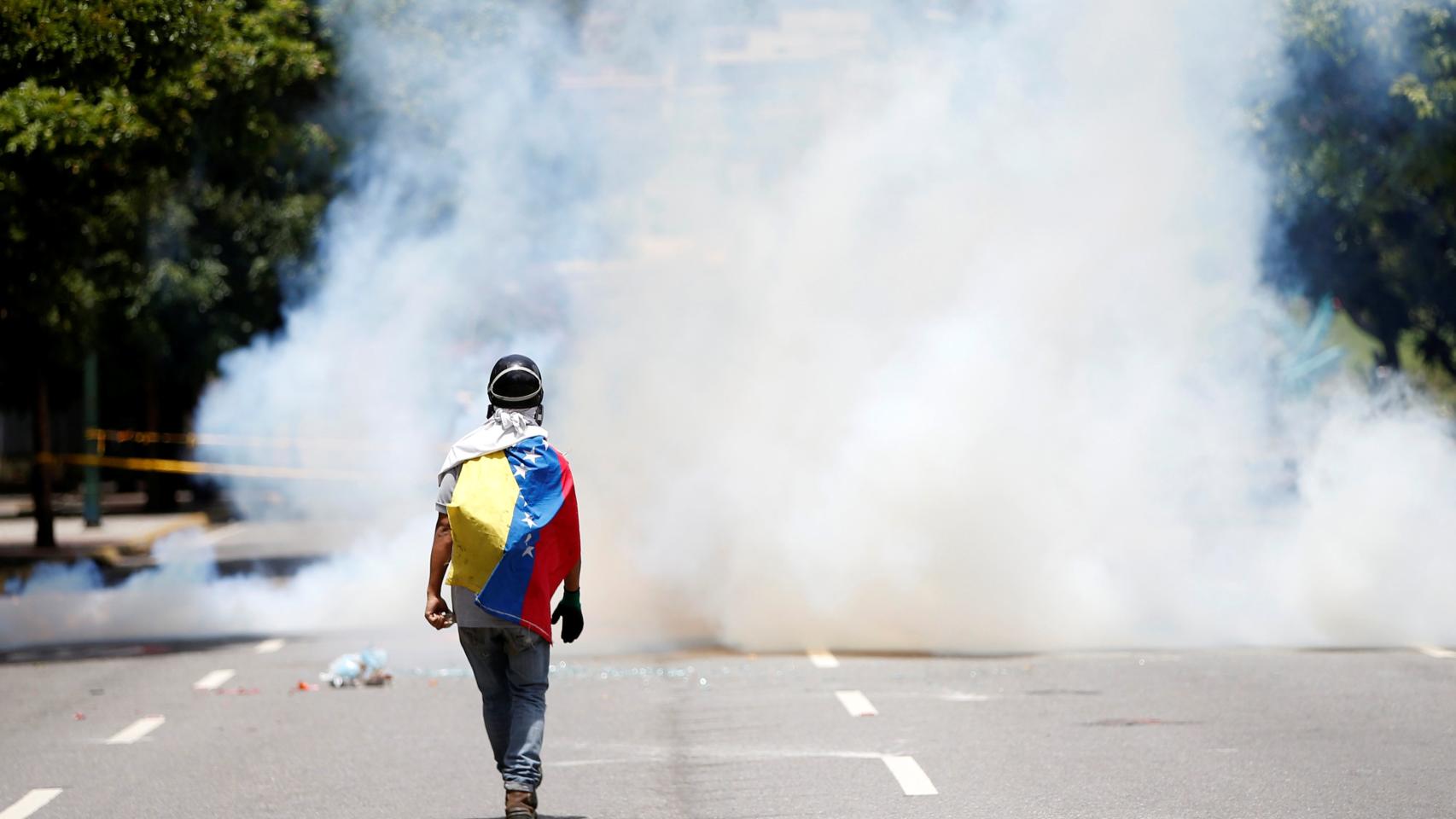 Un manifestante camina entre el humo en una protesta en Caracas. / Andres Martinez Casares / Reuters