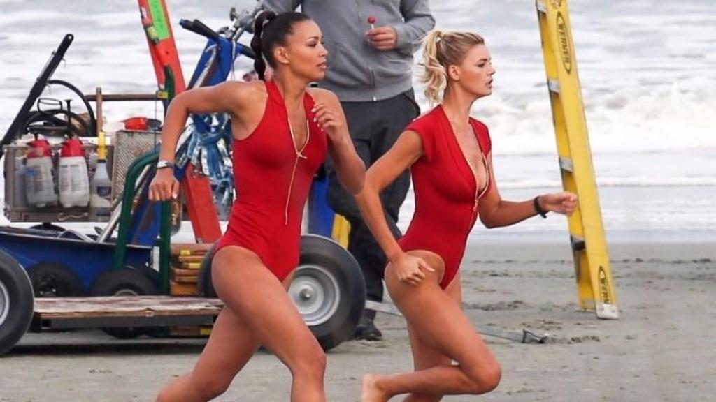 Escena de la película Baywatch: Los vigilantes de la playa (2017) donde las socorristas corren bajo el sol de la playa.