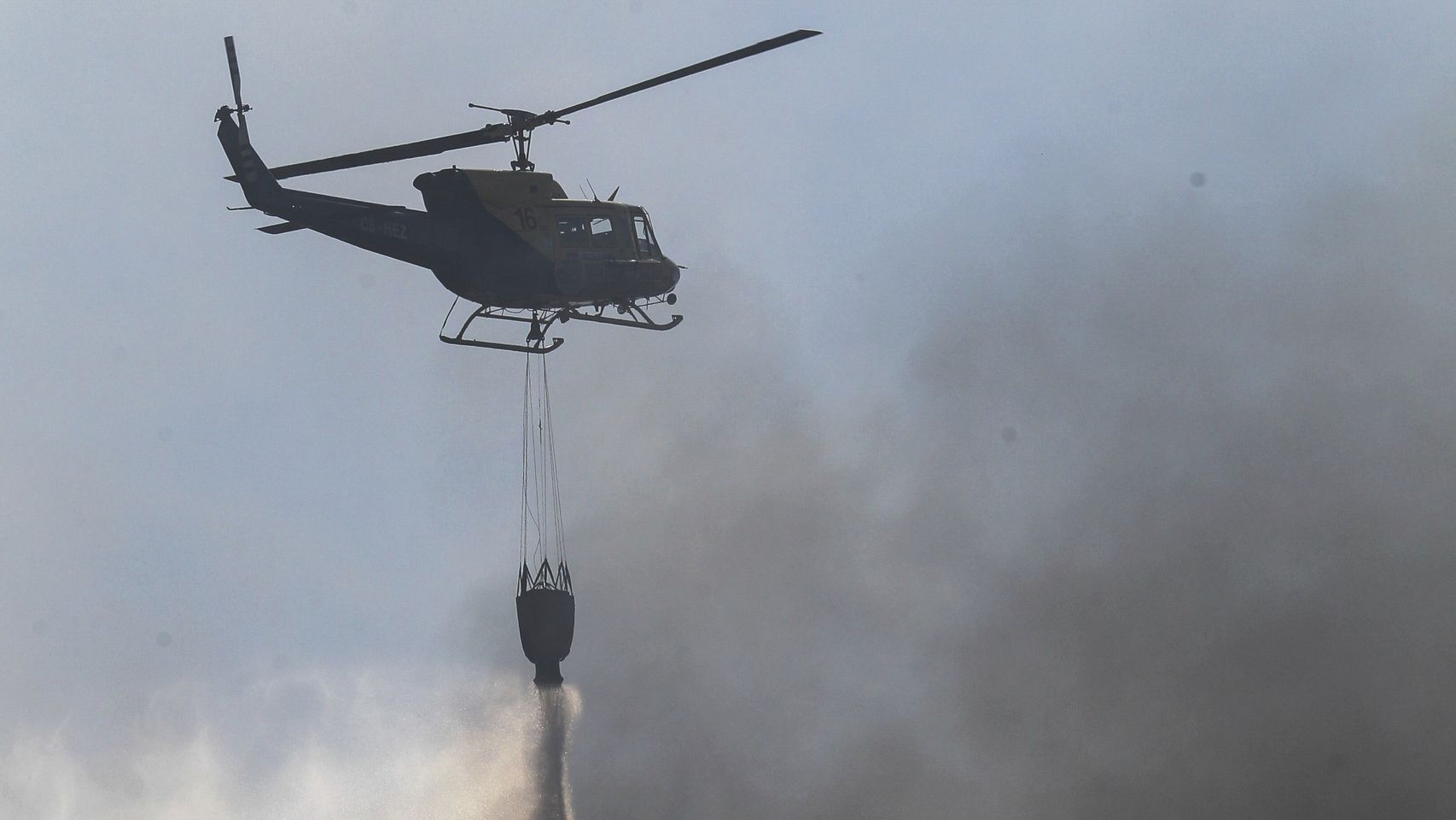Un helicóptero descarga agua sobre un incendio forestal