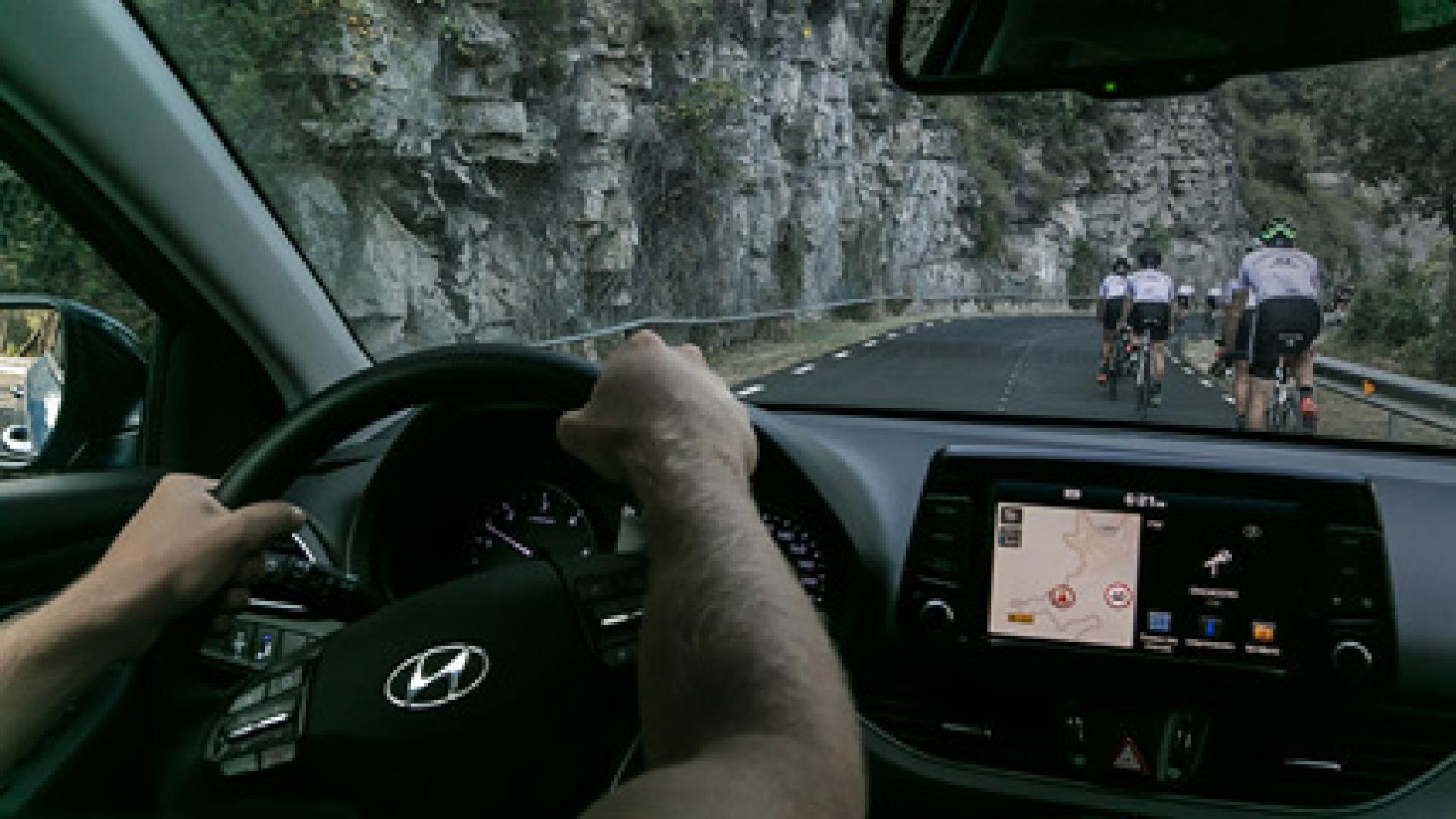 Un coche tras un grupo de ciclistas a modo de protección.