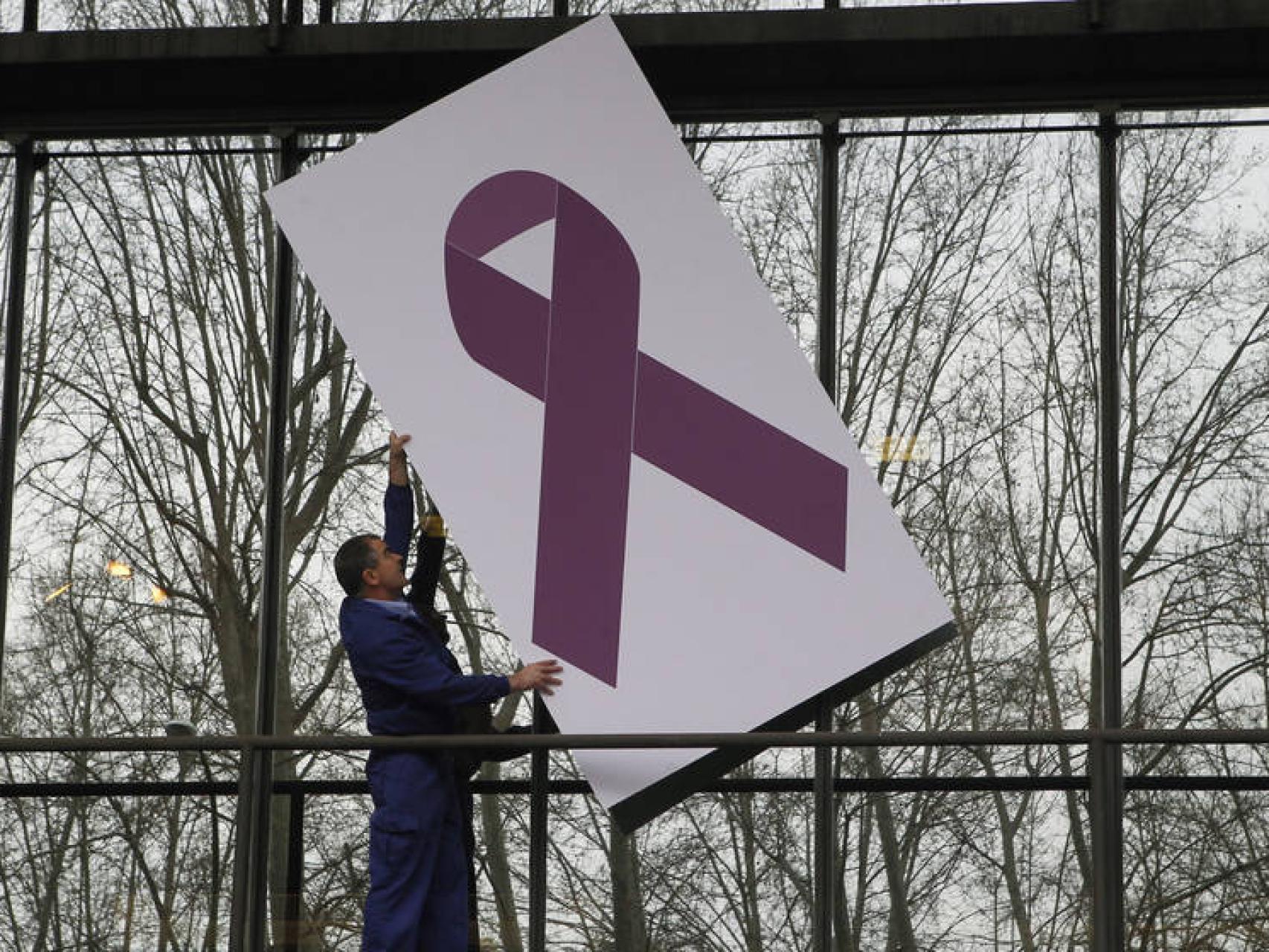 Un trabajador coloca un crespón morado en referencia a la violencia de género