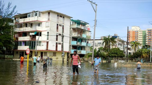 Varias personas caminan por una zona inundada por el huracán en La Habana.
