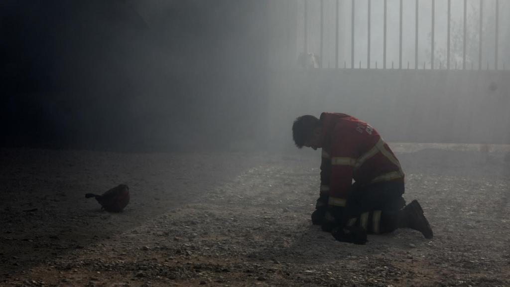 Un bombero arrodillado tras el combate al incendio en Portugal.