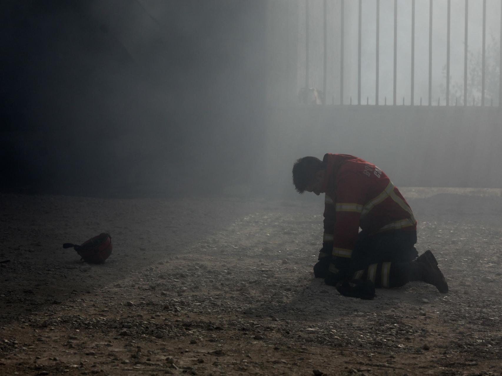 Un bombero arrodillado tras el combate al incendio en Portugal.