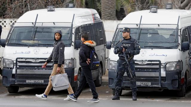 Unos jóvenes pasan por delante de los tanques desplegados en Túnez.