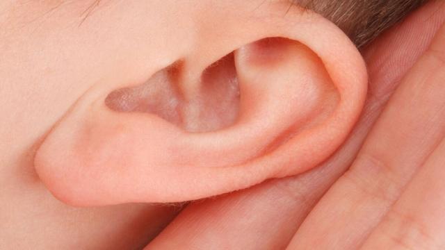 Un joven se acerca la mano a la oreja para escuchar mejor.