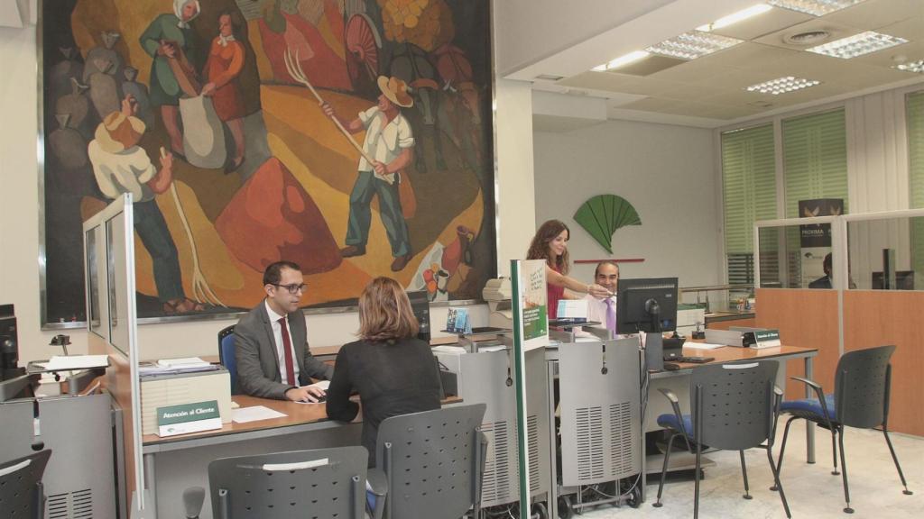 Un empleado de Unicaja atiende a una clienta en una sucursal de Castilla y León.