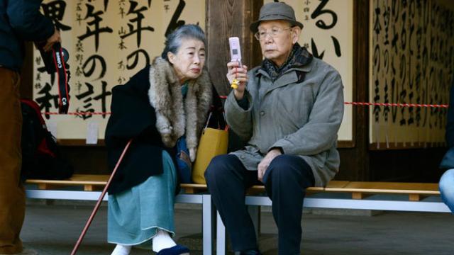 Una pareja japonesa consulta su teléfono móvil.