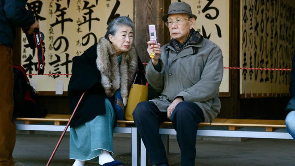 Una pareja japonesa consulta su teléfono móvil.