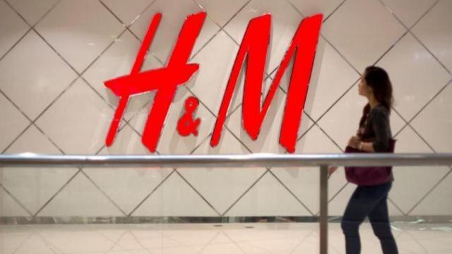 Una mujer pasea ante el logo de H&M.