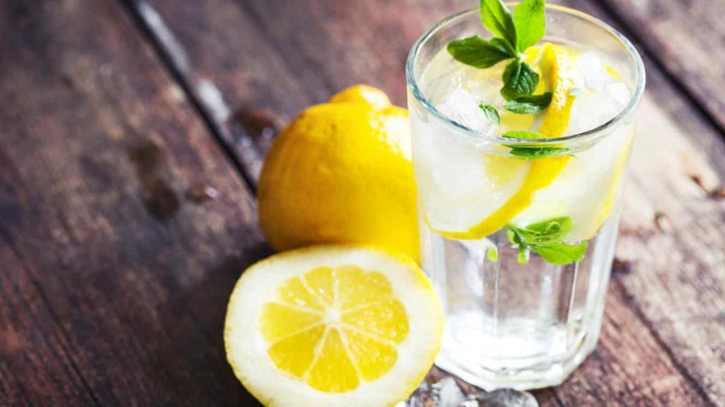 Un vasito de agua con limón dispuesto para ser bebido.