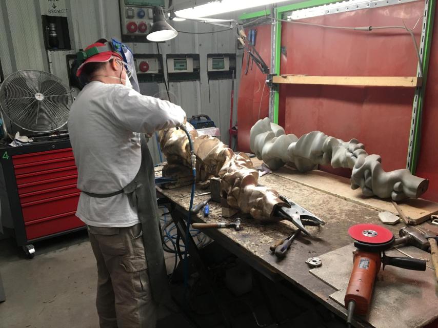 Un trabajador pule una pieza de Tony Cragg.