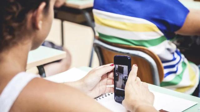 Una niña, utilizando el móvil en clase.