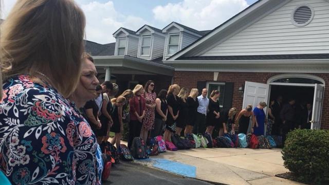 Los compañeros profesores de la mujer esperaban al féretro también con mochilas.