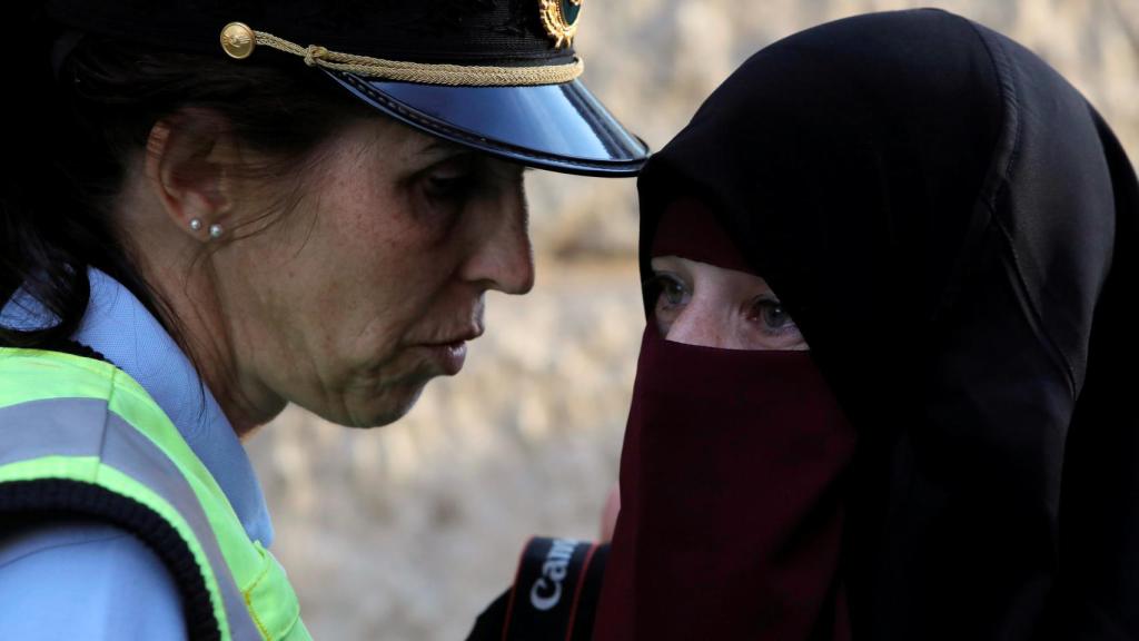 Una agente de seguridad junto a una mujer con niqab.