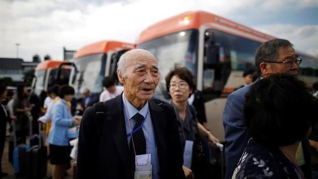 Un grupo de personas junto a los autobuses de traslado.
