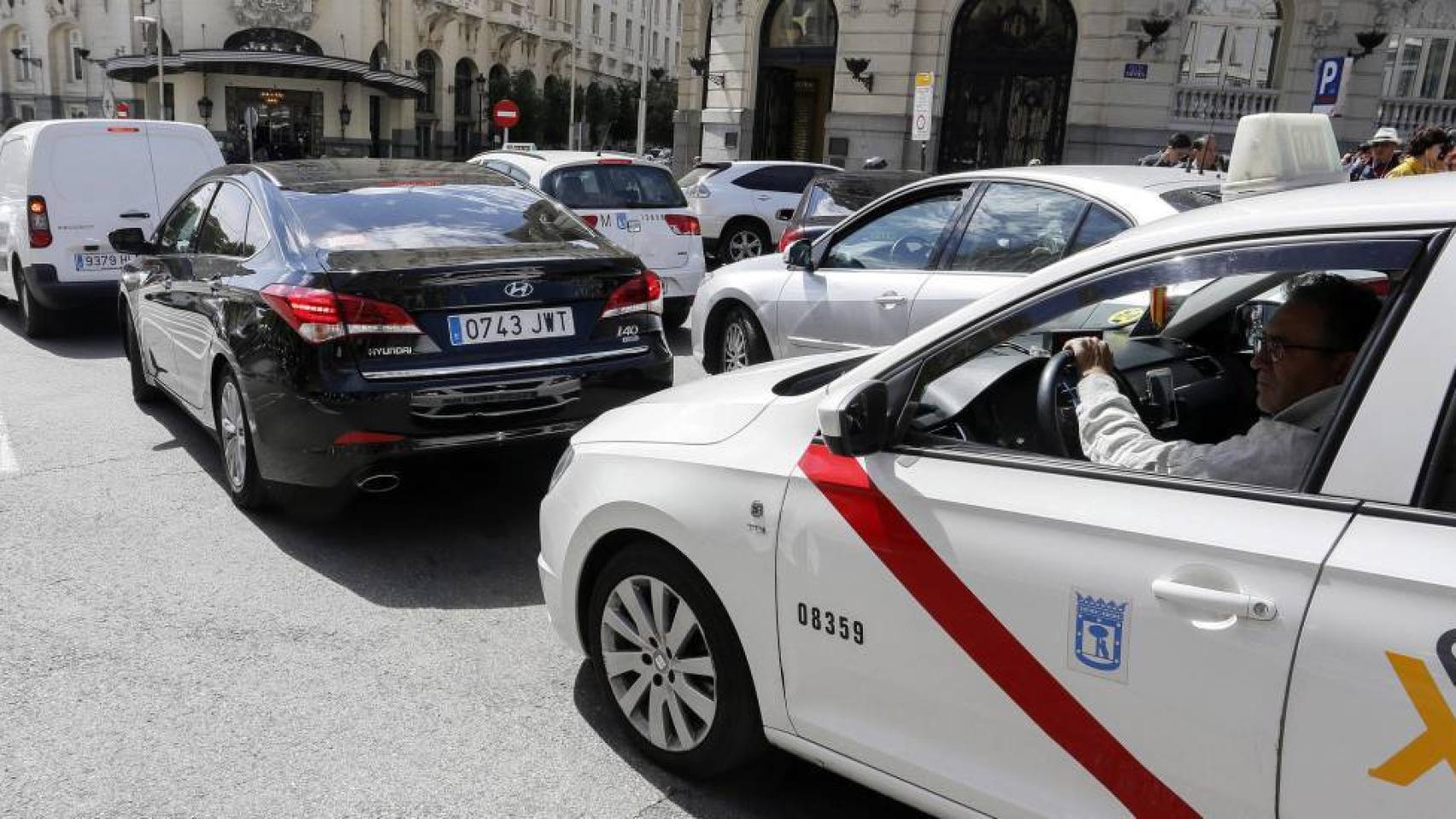Un taxi de Madrid detrás de un vehículo VTC en las calles de Madrid.