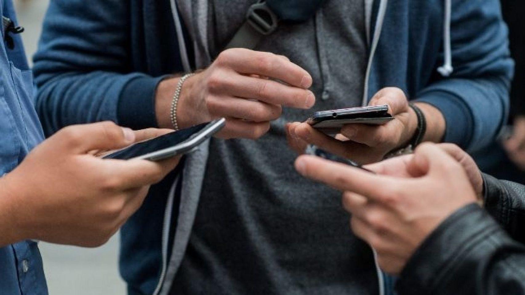 Un grupo de personas maneja sus teléfonos móviles.