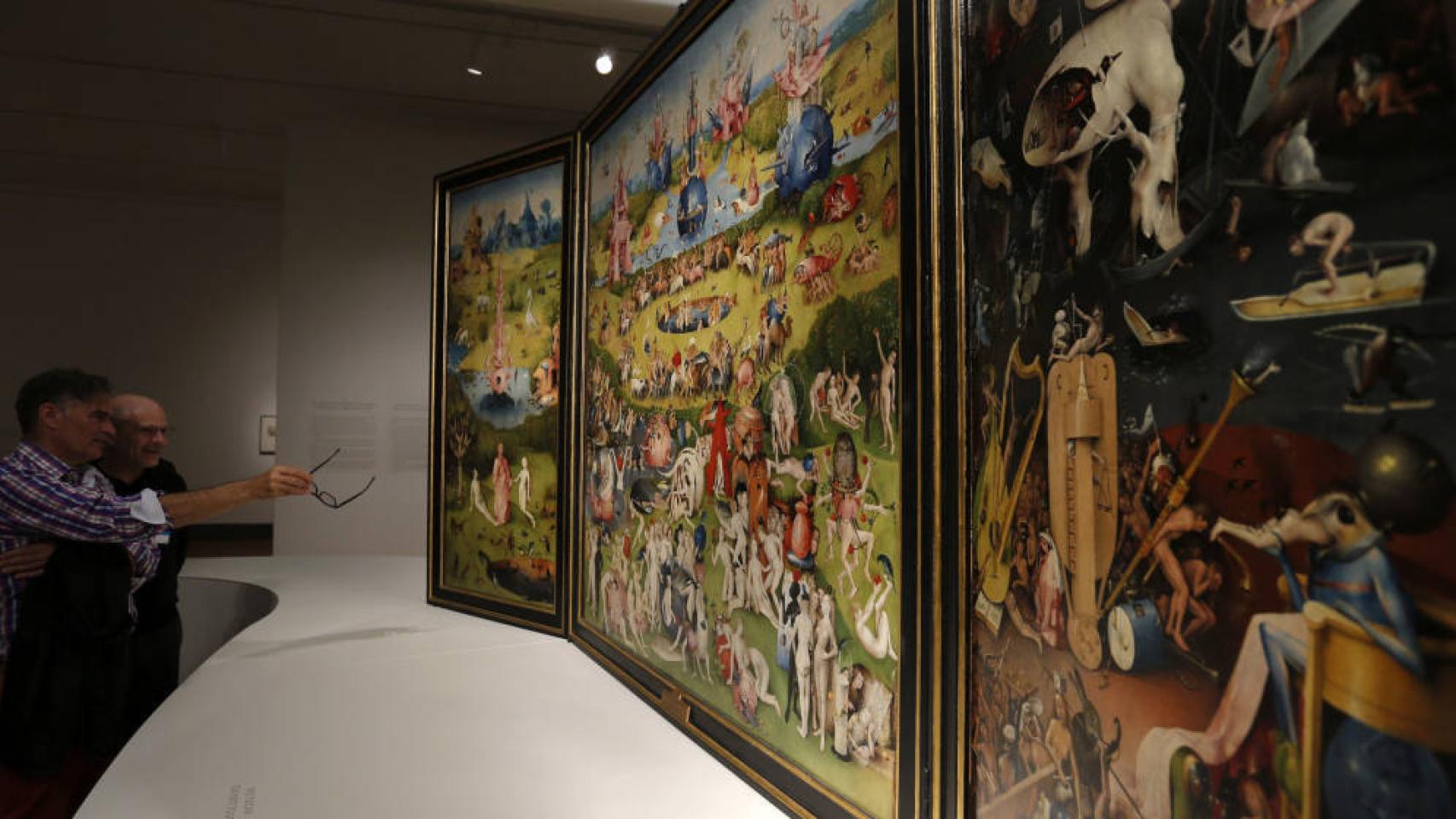 Dos hombres observan el 'Tríptico del jardín de las delicias', de El Bosco, en el Museo del Prado.