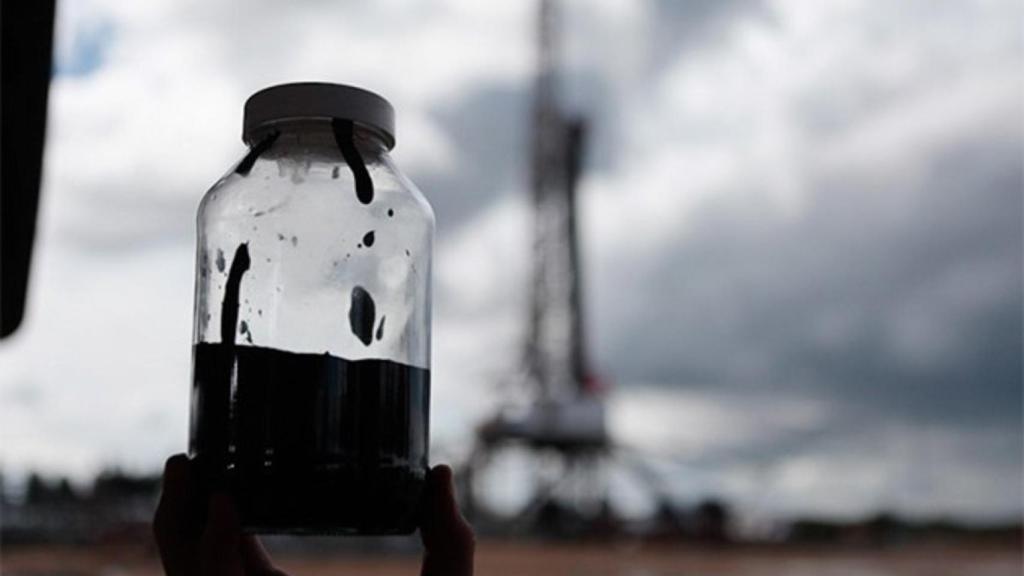 Un operario sostiene una muestra de crudo en una planta petrolífera.