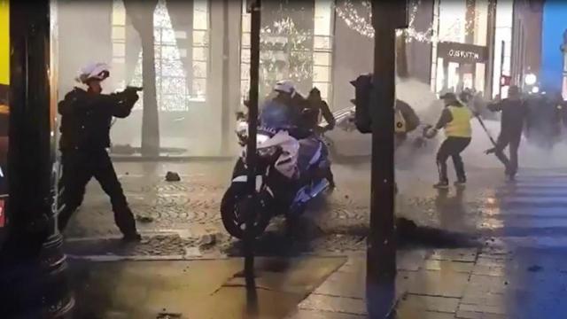 Un policía saca su arma en una protesta de los 'chalecos amarillos'