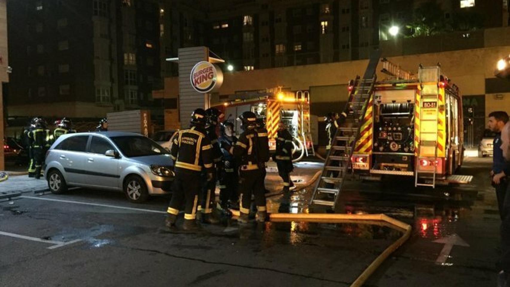 Los bomberos trabajan en el Burger King de Usera que ha sido desalojado por un incendio.